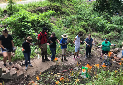 Youth form a chain in order to transport brick to the bottom of the stairs for the boulder landing area