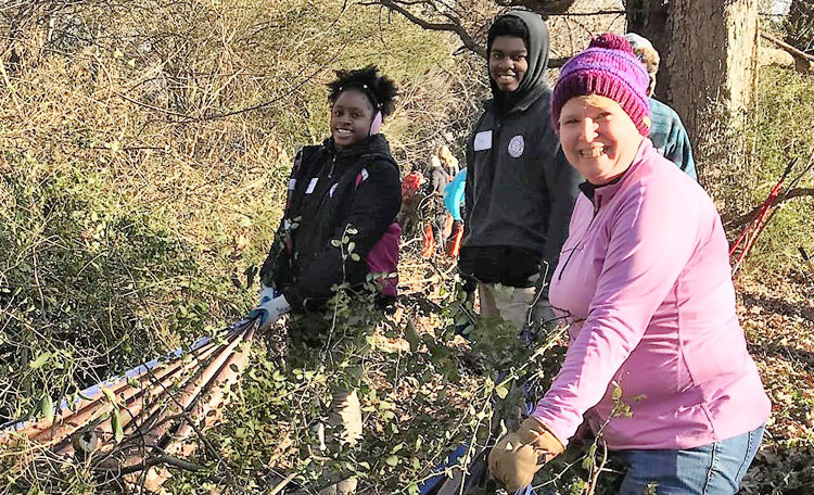 MLK Day of Caring volunteers pulling weeds and smiling