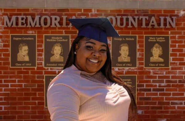 Head shot of LaQuisha - former LMC intern. Black woman with blue graduation cap on smiling