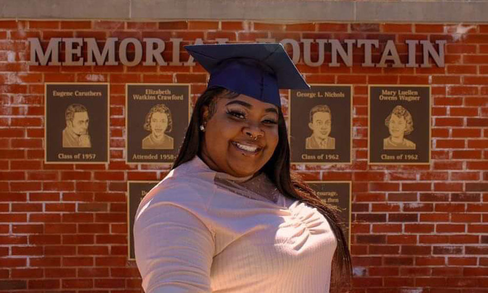 Head shot of LaQuisha - former LMC intern. Black woman with blue graduation cap on smiling