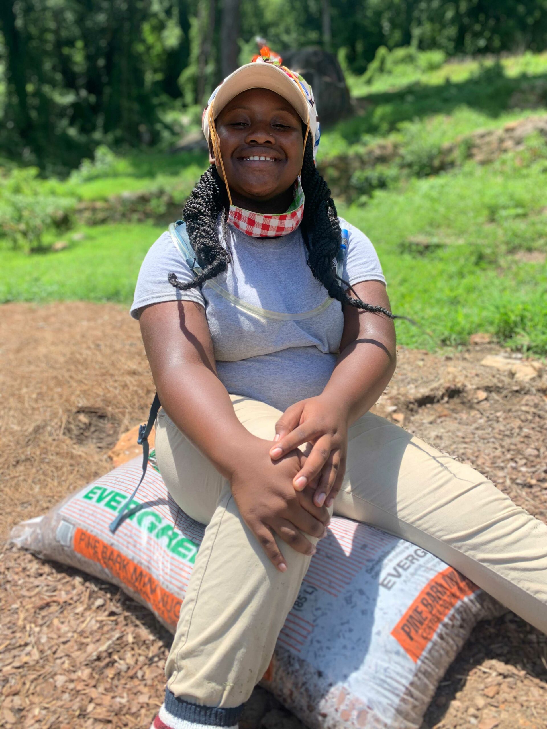 Intern Ramiyah sitting on a bag of mulch