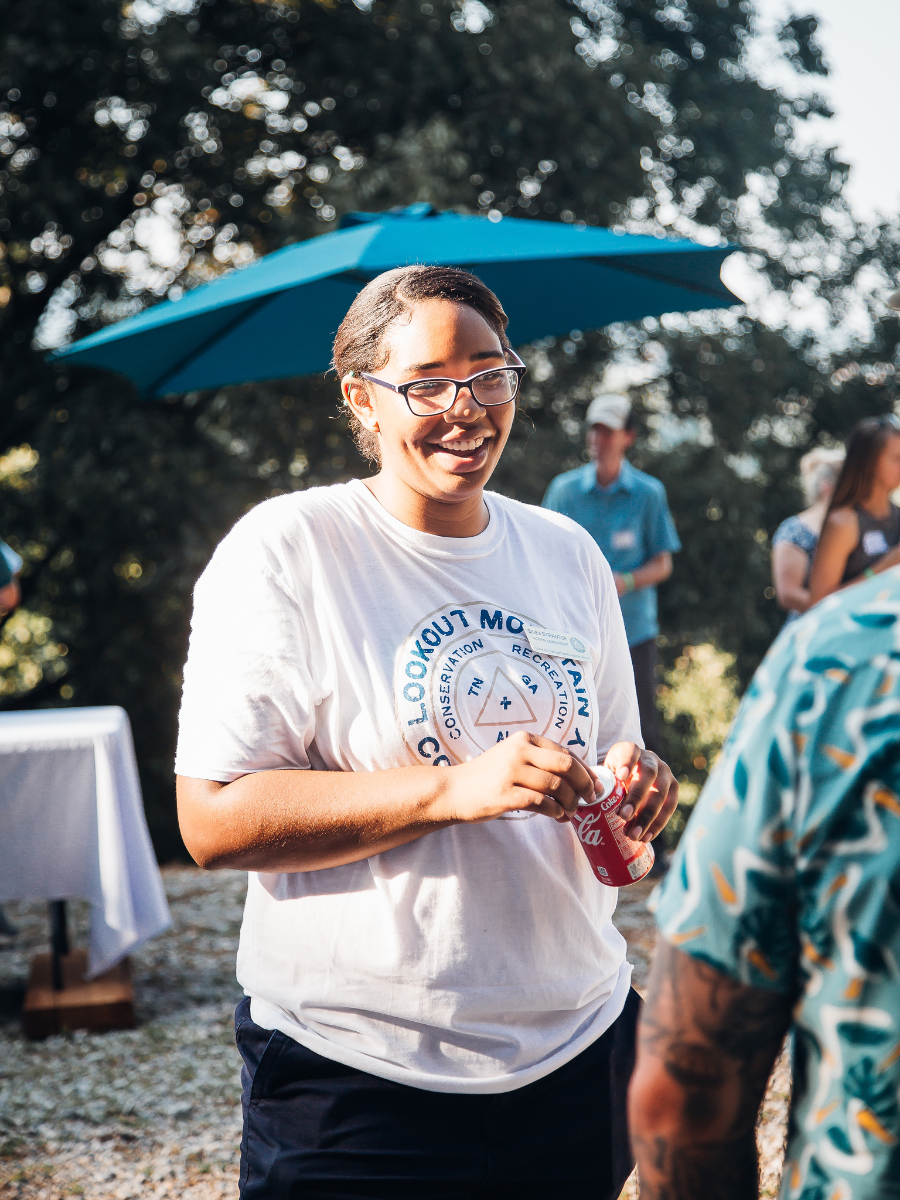 Candid Shot of a young black woman in a white shirt with a black bun and glasses laughing at something off camera