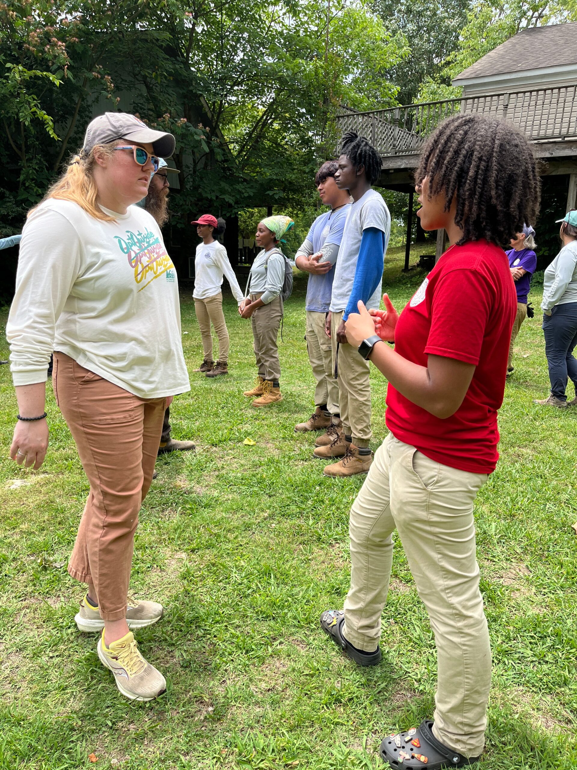 (left) middle-aged white female in a white shirt speaking with a young black female in a red shirt (right)